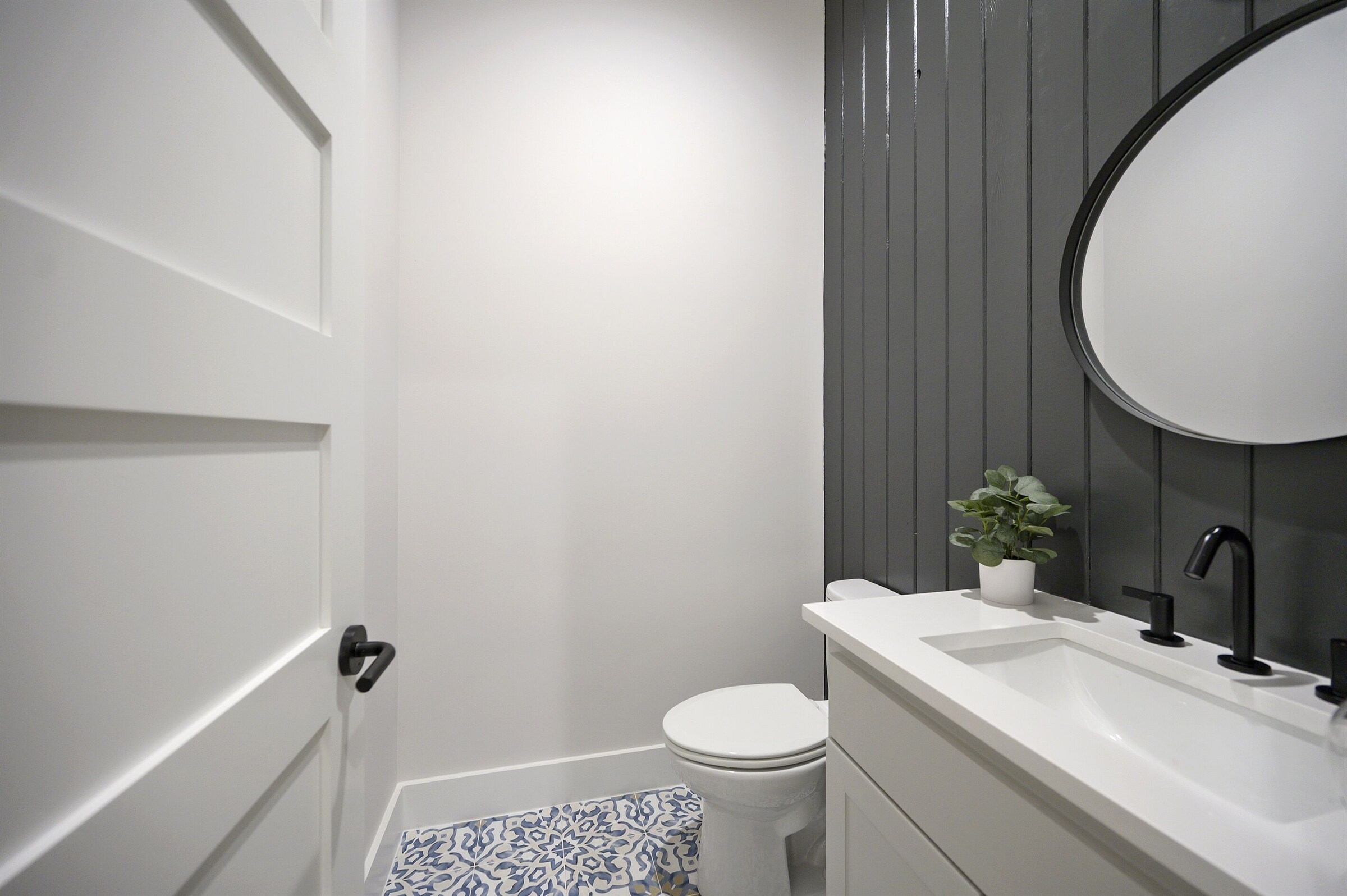 Bathroom with a round mirror and black fixtures